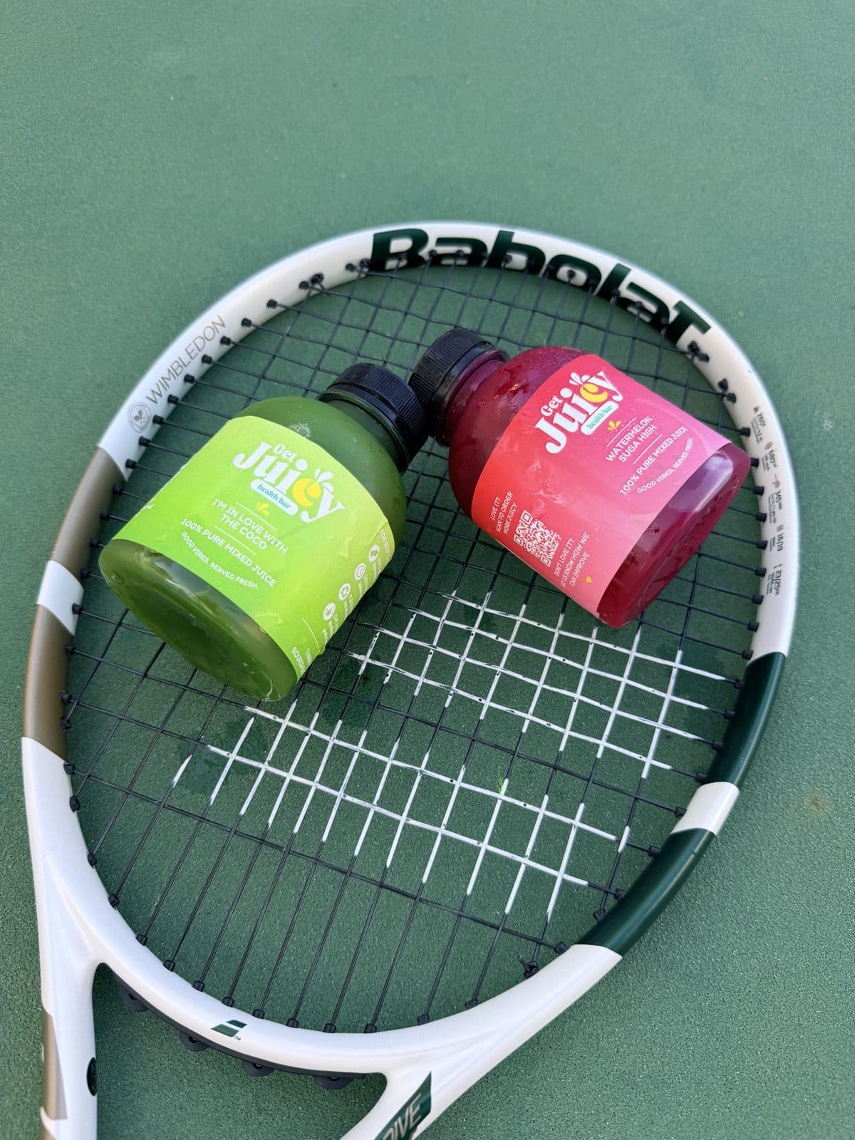 Two bottles of Juicy Pops on a tennis racket