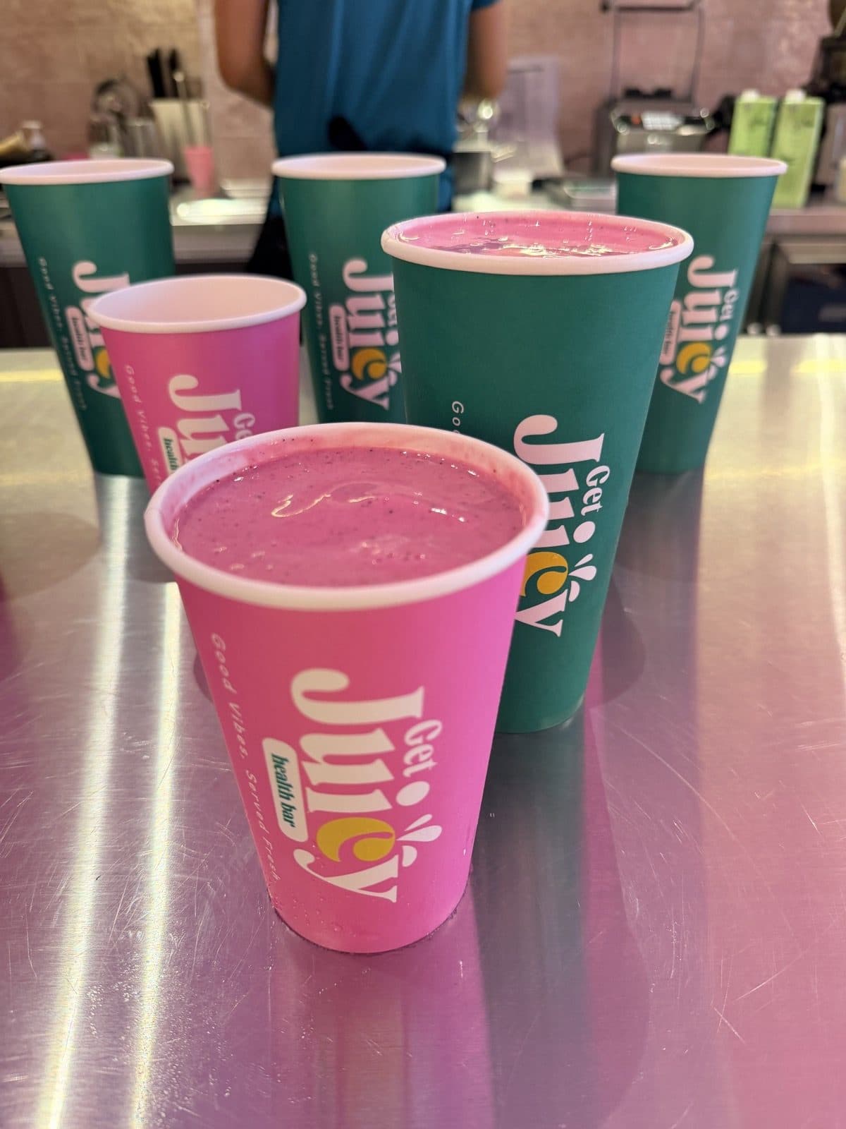 Juicy smoothies in pink and green cups on the counter