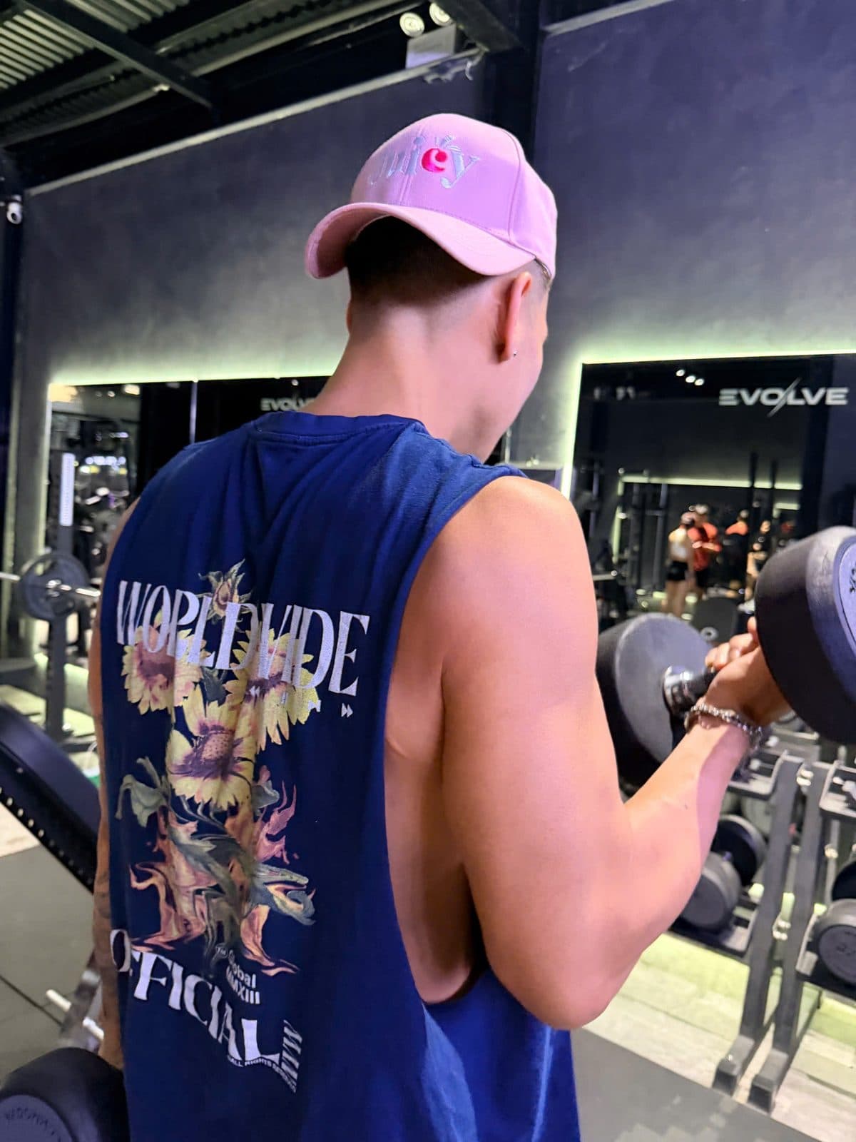 A man training at a gym in a Juicy cap