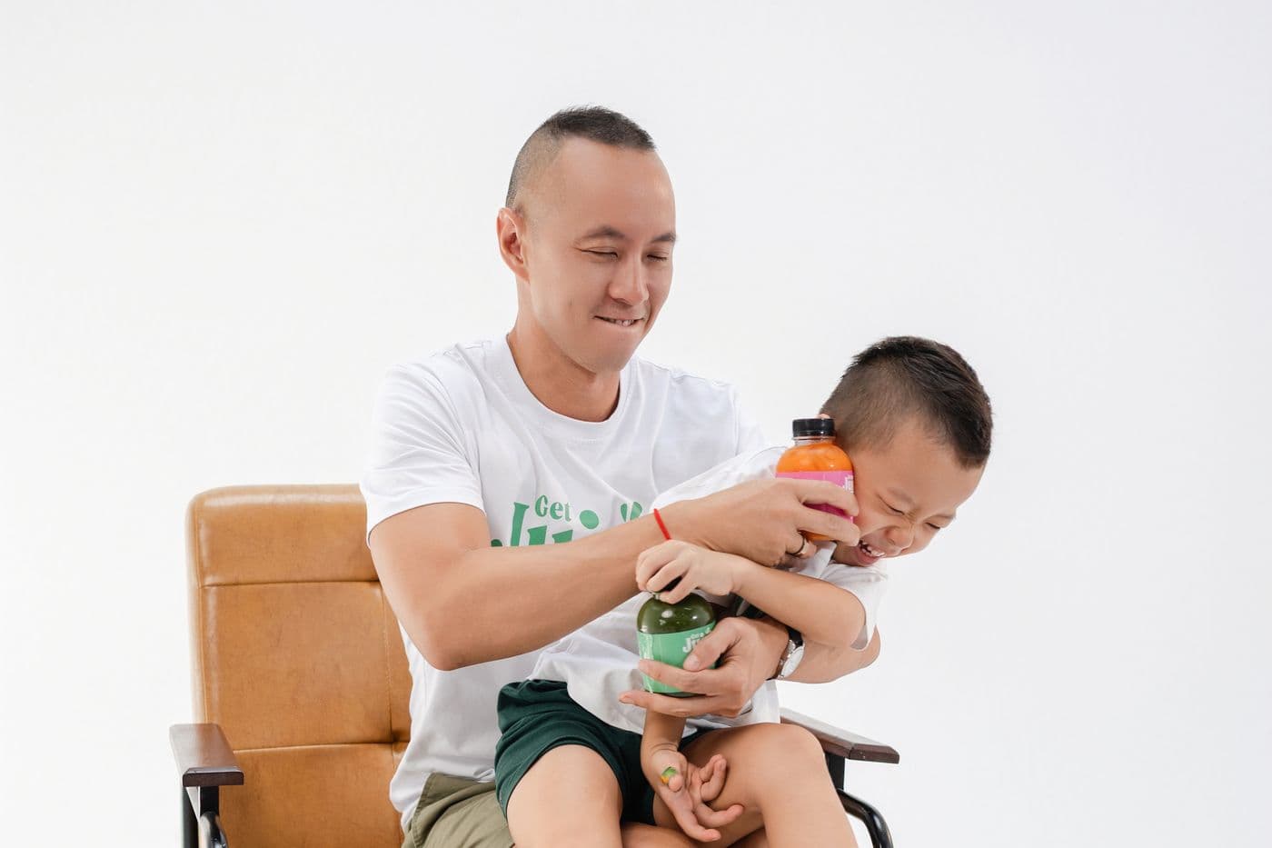 Linh cười, Sky ngồi trên đùi, cả hai cùng cầm chai nước